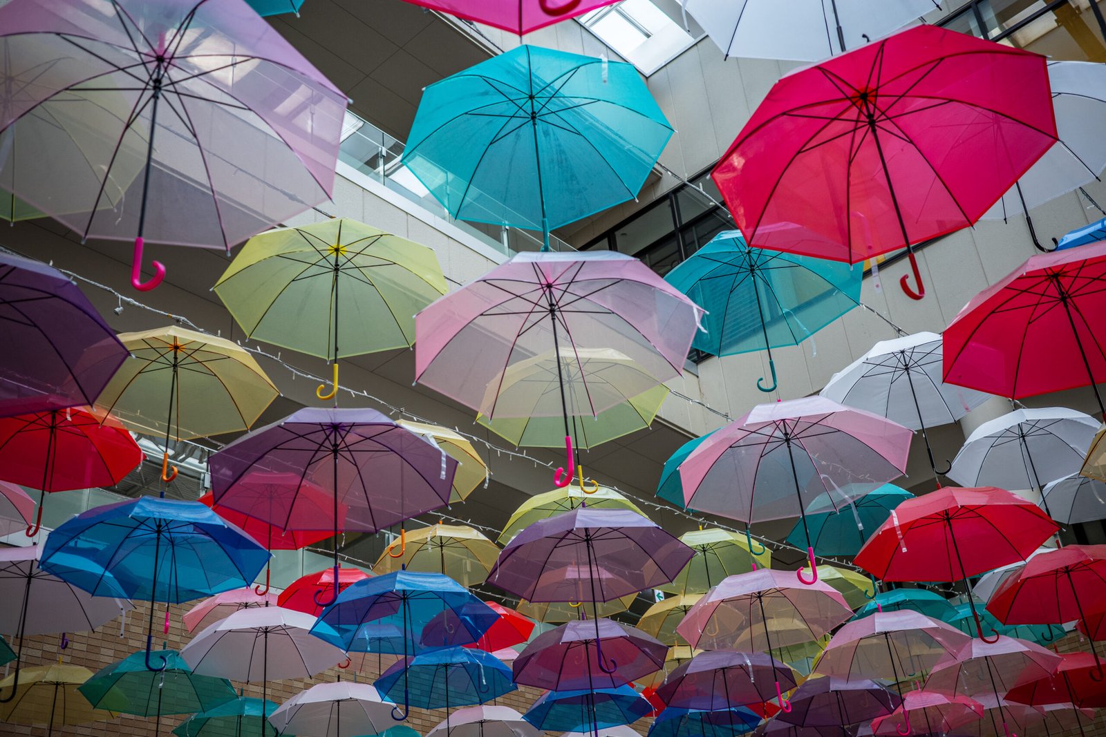 A display of decorative, brightly colored umbrellas on the ceiling of an indoor mall.